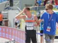 Krzysztof Różnicki, lekkoatleta, po biegu z dłonią na czole, obok niego stoi mężczyzna w niebieskiej koszulce.