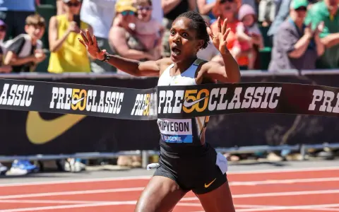 Faith Kipyegon przekracza linię mety z uniesionymi rękami, triumfując na bieżni.