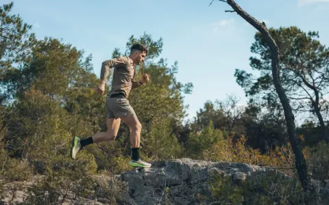 Mężczyzna w letniej odzieży sportowej pokonuje kamienisty teren, doskonaląc swój trening biegowy metodą Skarzyńskiego.