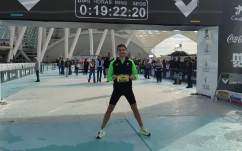 Uśmiechnięty Dariusz z numerem 1360 na piersiach po biegu na maratonie Valencia. Czas na tablicy: 0:19:22:20.