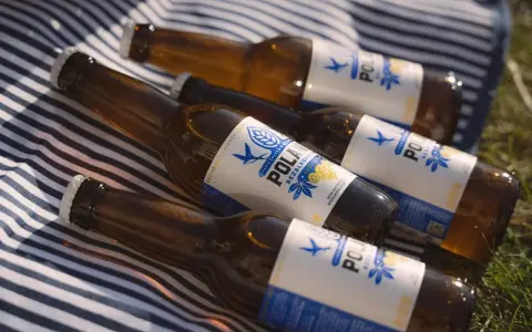 Idealne piwo po bieganiu: cztery butelki bezalkoholowego napoju na kocu w paski.