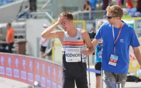 Krzysztof Różnicki, lekkoatleta, po biegu z dłonią na czole, obok niego stoi mężczyzna w niebieskiej koszulce.